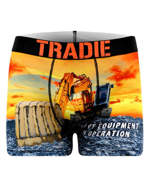 The Tradie Mens Work N Surf Trunk features a bold print of a yellow excavator and bulldozer against an orange sunset, moisture-wicking quick-dry fabric, and an orange "TRADIE" waistband.