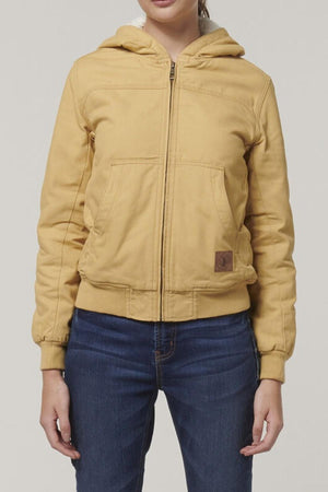 A person in a Hard Yakka Women's Bomber Jacket, light brown with fleece lining, zipper, two front pockets (one has a small patch), paired with blue jeans. The background is plain light gray.