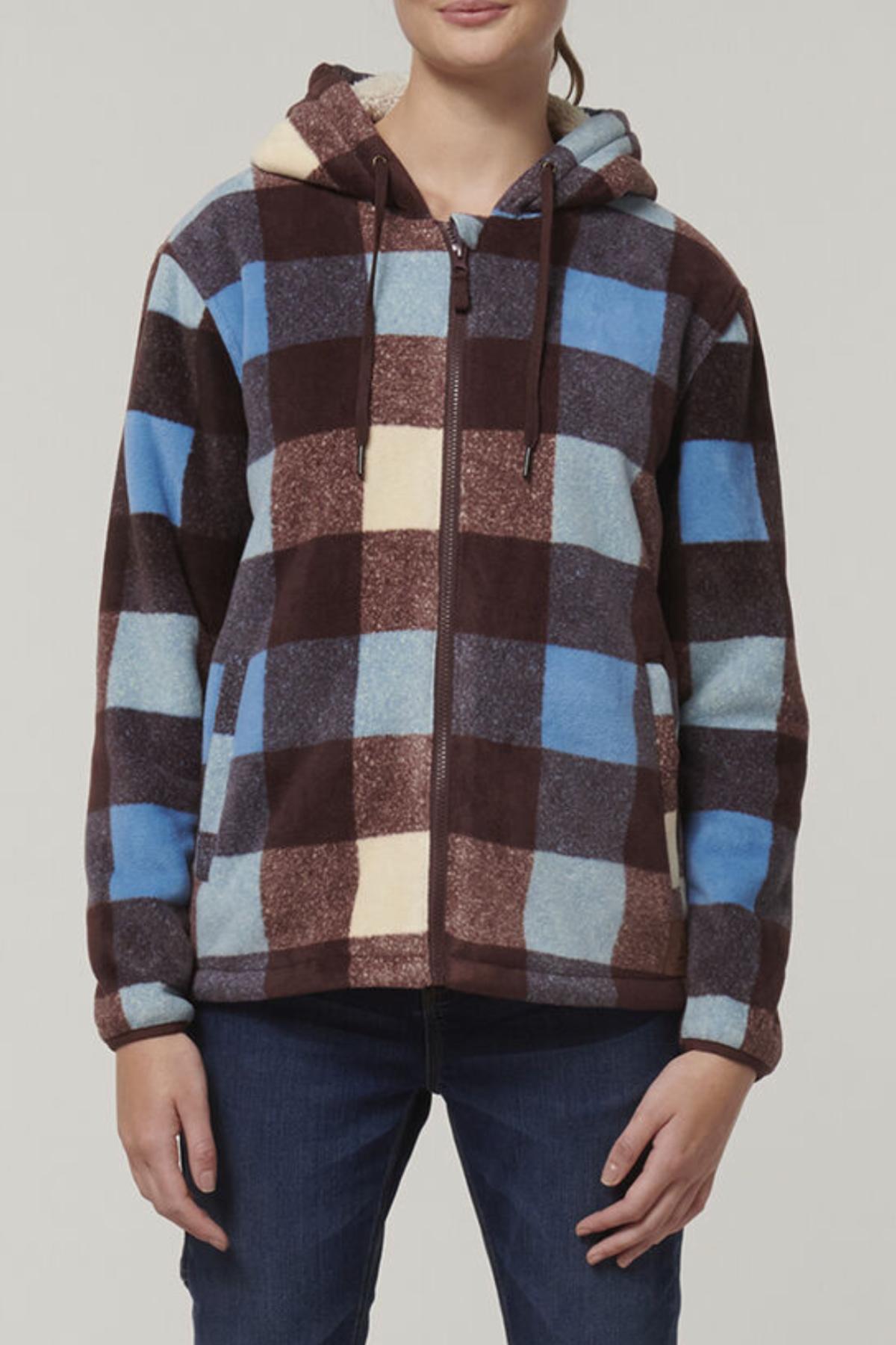 A person wearing the Hard Yakka Womens Check Zoodie, featuring a fleece body and large check pattern in brown, blue, cream, and maroon, with dark blue jeans stands against a plain light background.