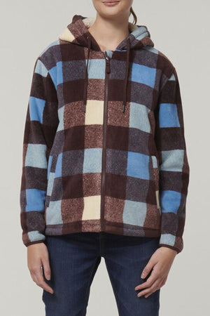 A person wearing the Hard Yakka Womens Check Zoodie, featuring a fleece body and large check pattern in brown, blue, cream, and maroon, with dark blue jeans stands against a plain light background.