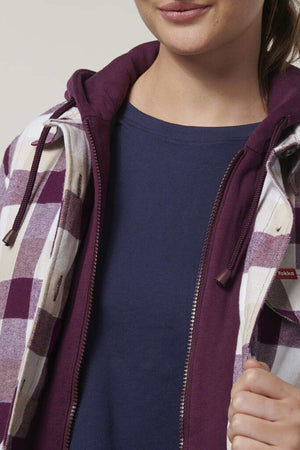 Wearing a "Hard Yakka Womens Quilted Shacket," this person pairs it with a blue shirt and purple hoodie. The partially zipped, purple-and-white checkered jacket has a durable quilted lining, and they grasp its edges with one hand, revealing only part of their face.