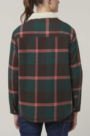 A woman with brown hair in a ponytail wears the Hard Yakka Women's Heritage Trucker Sherpa Jacket, featuring green, red, and black plaid with a white sherpa collar, shown from the back against a plain background.