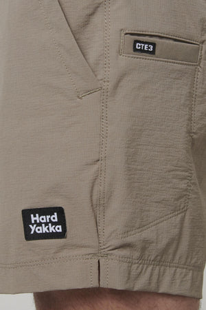 A close-up of the beige Hard Yakka X Short Short features two patches: "Hard Yakka" near the hem and "CTE3" above the pocket. These shorts are made from durable Cordura Nylon with 4-way stretch for unparalleled comfort.