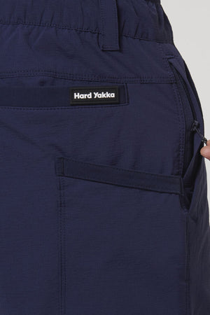 Close-up of a hand pulling a zipper next to the pocket of Hard Yakka X Short Short, showing durable Cordura Nylon fabric and the visible "Hard Yakka" label above the pocket.