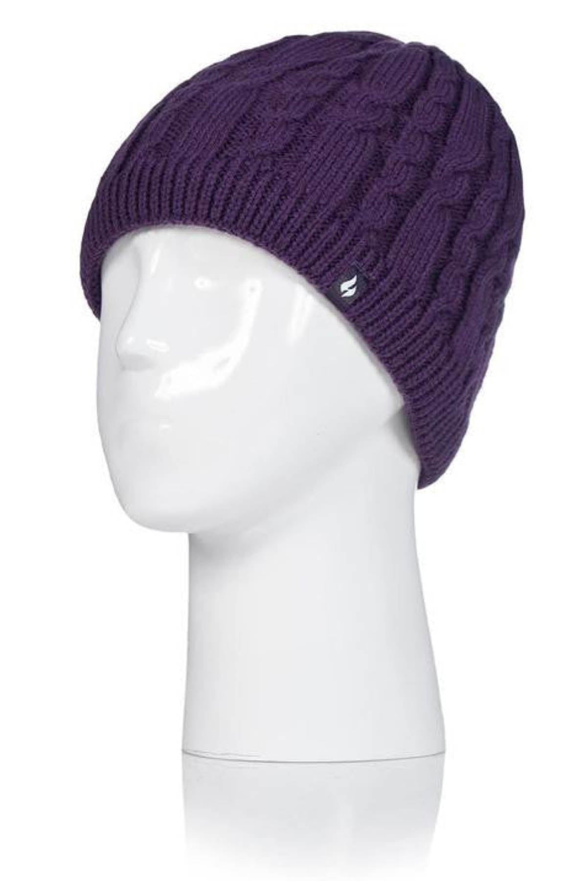 The Heat Holders Alesund Ladies Thermal Beanie, in purple with a cable-knit design, is displayed on a white mannequin head. The beanie features HeatWeaver plush lining for added warmth and has a small metallic logo tag attached near the brim.