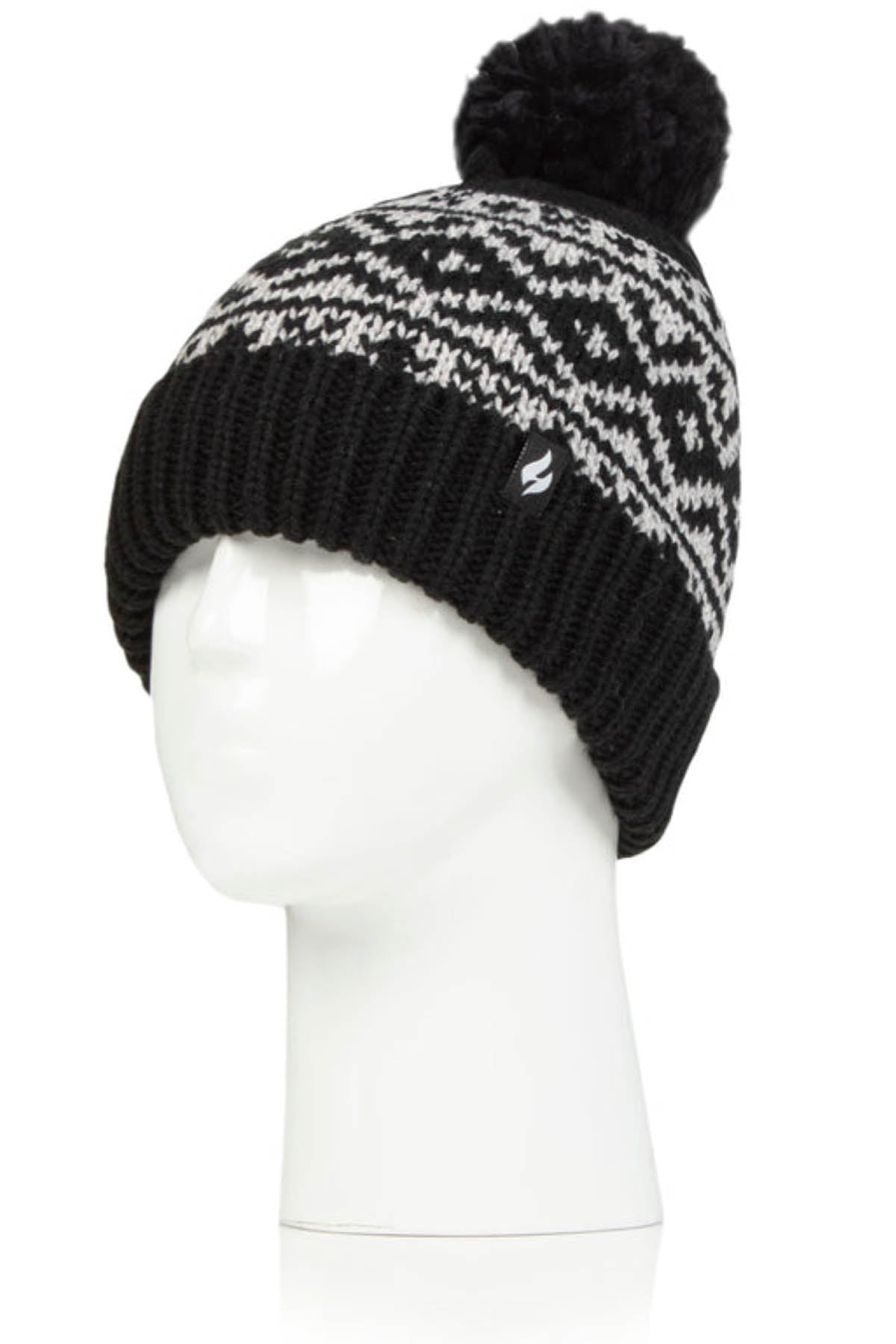 The Heat Holders Aspen Pom Pom Turn Over Ladies Thermal Beanie, featuring a black and white knit design with a geometric pattern and a large pom-pom on top, is displayed on a white mannequin head. This hat includes a turned-up ribbed cuff with a small logo tag on the side, designed to keep you warm with its HeatWeaver thermal lining.