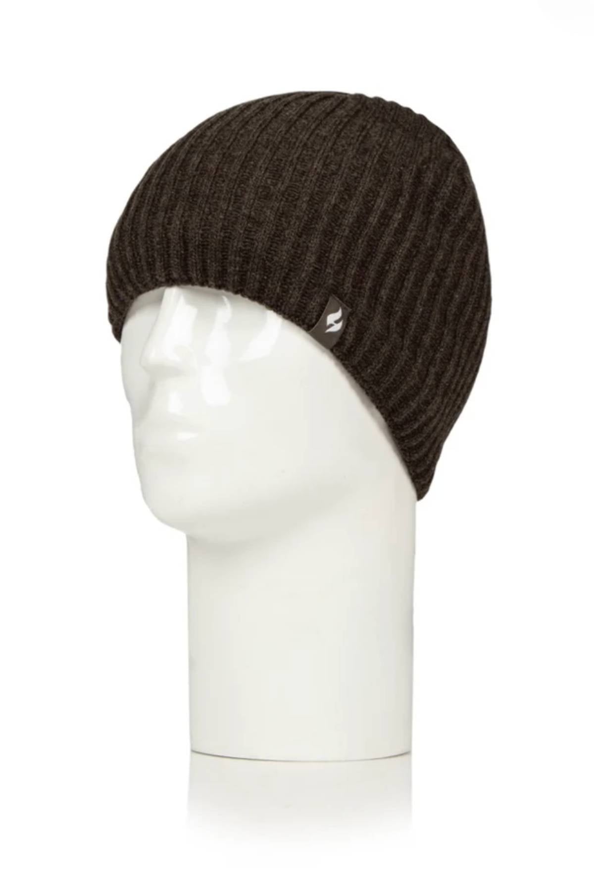 The Heat Holders Halden Mens Thermal Beanie, in dark brown ribbed knit, is shown on a white mannequin head in side profile. This winter hat features a small metallic side tag and provides stylish warmth.
