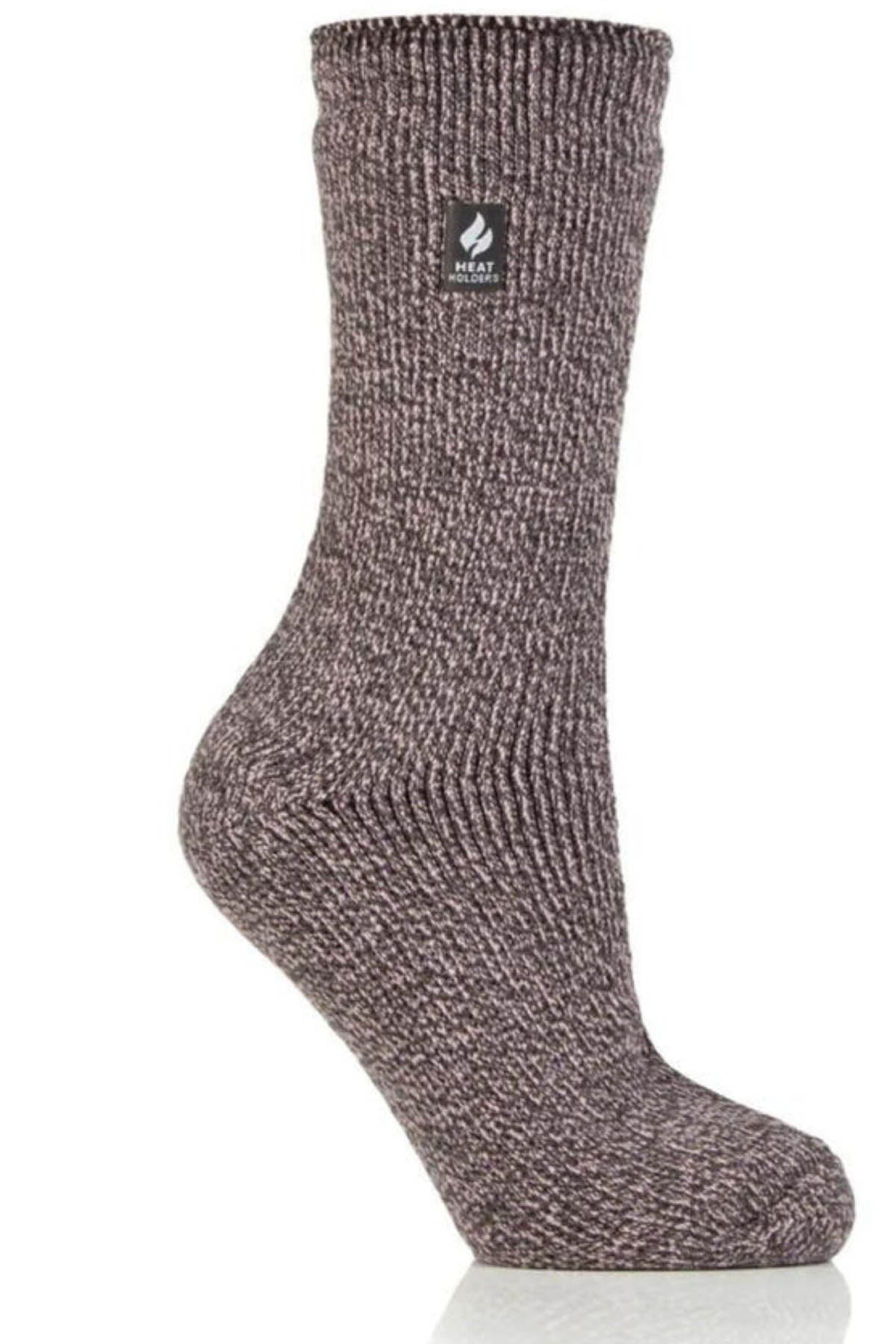 A single Heat Holders Ladies Wool Sock, crafted from gray ribbed-knit wool, is presented with a side profile view. Its textured appearance extends to mid-calf length. Near the top, a small black label featuring a flame icon and the text "Heat Holders" is visible. Known for its exceptional warmth, the sock is set against a white background.