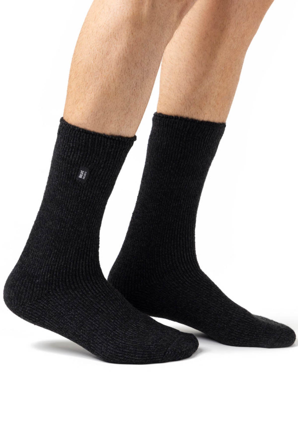 A picture of a person wearing the Original Thermal Heat Holders Sock, which are dark gray, ribbed, and mid-calf in length, designed specifically for cold weather. Only the legs and feet are visible against a white background. These warm socks feature a small black tag with white text near the top, underscoring their superior warmth and comfort.