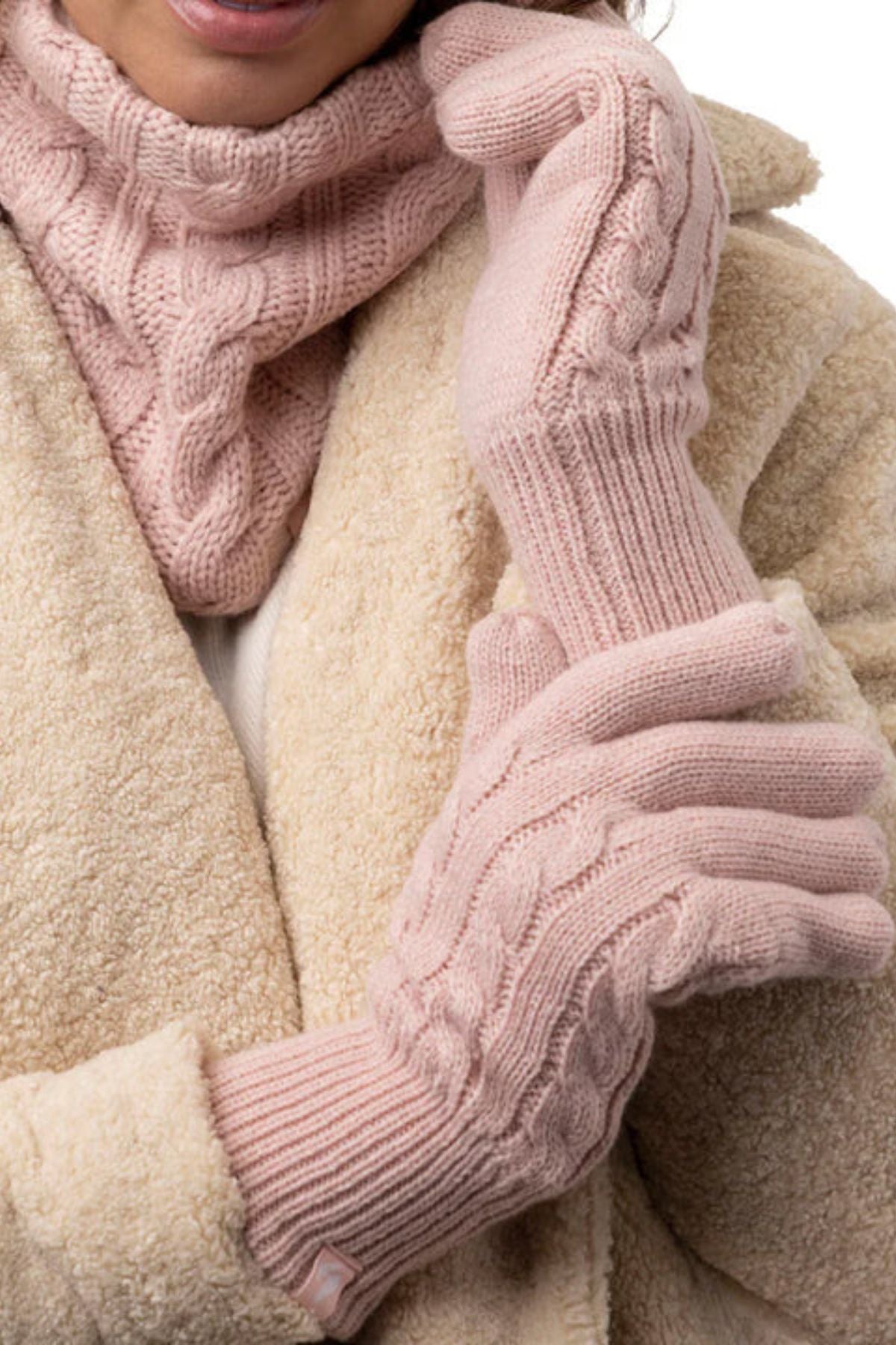 A person in a soft beige coat, a pink cable-knit scarf, and Heat Holders Willow Ladies Thermal Gloves holds one gloved hand with the other, highlighting these cozy thermal gloves and stylish winter accessories.