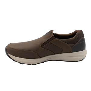 The Florsheim Excursion Slip On is a brown leather shoe featuring a white sole with shock absorption, a textured black heel area, and visible stitching for comfort and durability. The shoe's design ensures every step is easy, being positioned facing left.