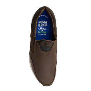 Top view of a brown slip-on shoe with textured fabric around the ankle. The visible insole displays the brand "Florsheim" and mentions sustainable foam designed for optimal shock absorption.