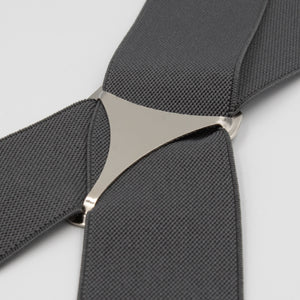 Close-up of Buckle Plain Braces in dark gray, featuring adjustable straps and a silver triangular connector, displayed on a light gray background.