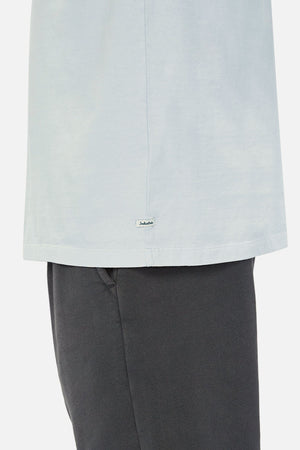 A close-up side view of a person in the Industrie The Del Sur Tee in light blue with a brand tag near the hem—ideal for checking our size guide and ensuring an accurate chest measurement.