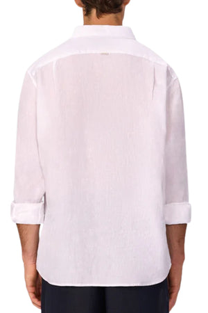 A person is shown from the back wearing the Industrie The St Martins Shirt—a long-sleeve, white linen shirt with a straight collar, relaxed fit, rolled-up sleeves, and breathable fabric—paired with dark pants.