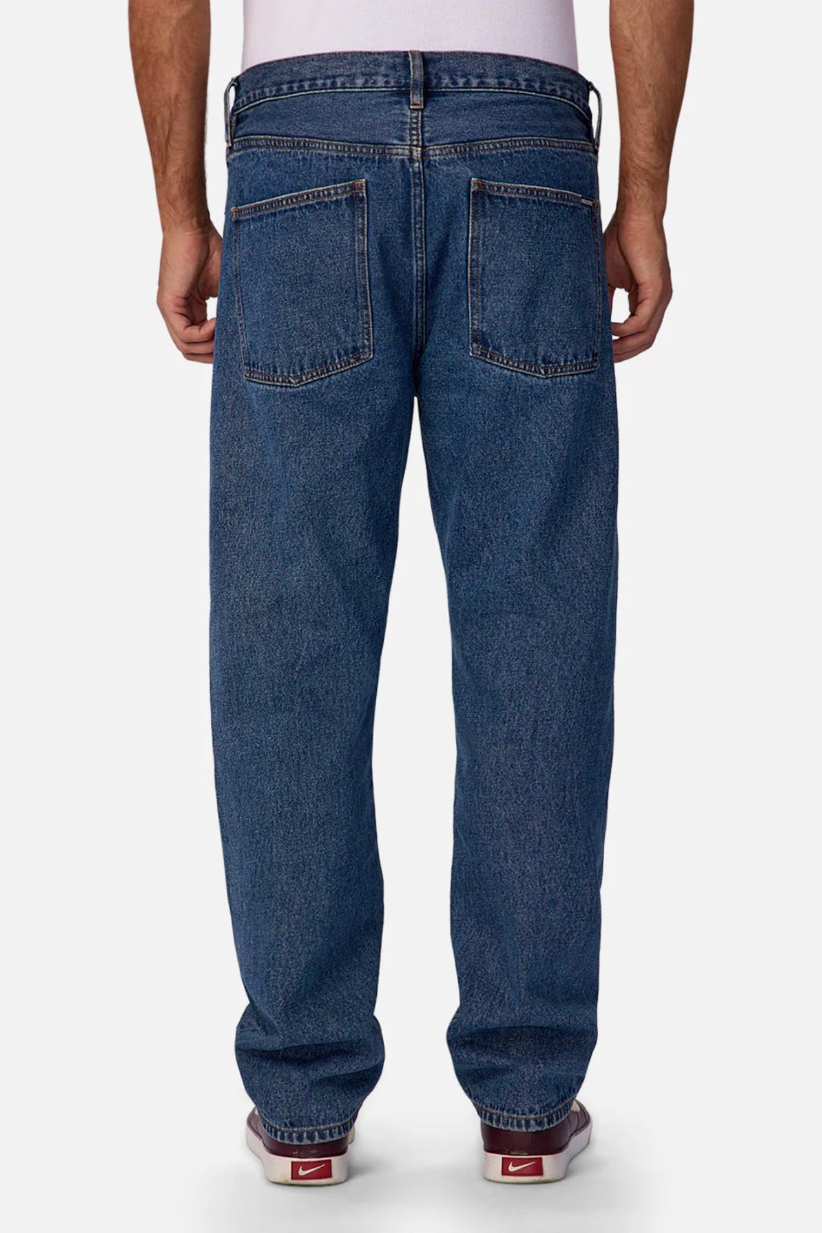 A person is seen from behind wearing Industrie The 90's Jeanβrelaxed, straight-leg, 100% cotton vintage-washed denim with two large back pockets and visible stitchingβpaired with red Nike sneakers against a plain white background.