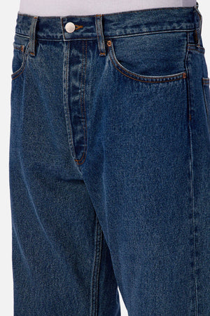 Close-up of a person wearing Industrie The 90's Jean, made from 100% cotton vintage washed denim with front pockets, metal button, and zipper fly, paired with a tucked-in white shirt.
