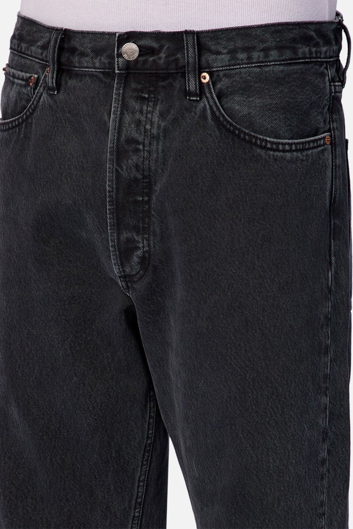 Close-up of a person wearing Industrie The 90's Jean, featuring high-waisted black vintage washed denim, front pockets, metal button, detailed stitching, and a relaxed straight leg cut for an authentic 90's vibe.