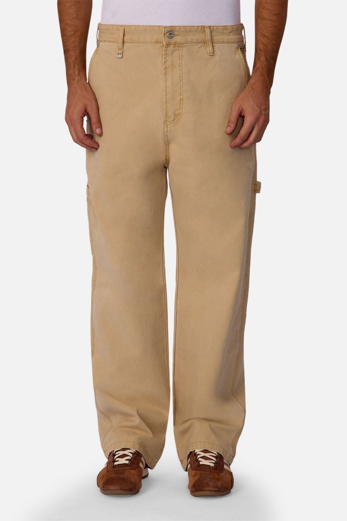 A person wears Industrie The Carolina Carpenter Pant, featuring loose-fitting, durable cotton and utility pockets, paired with brown shoes against a plain white background.