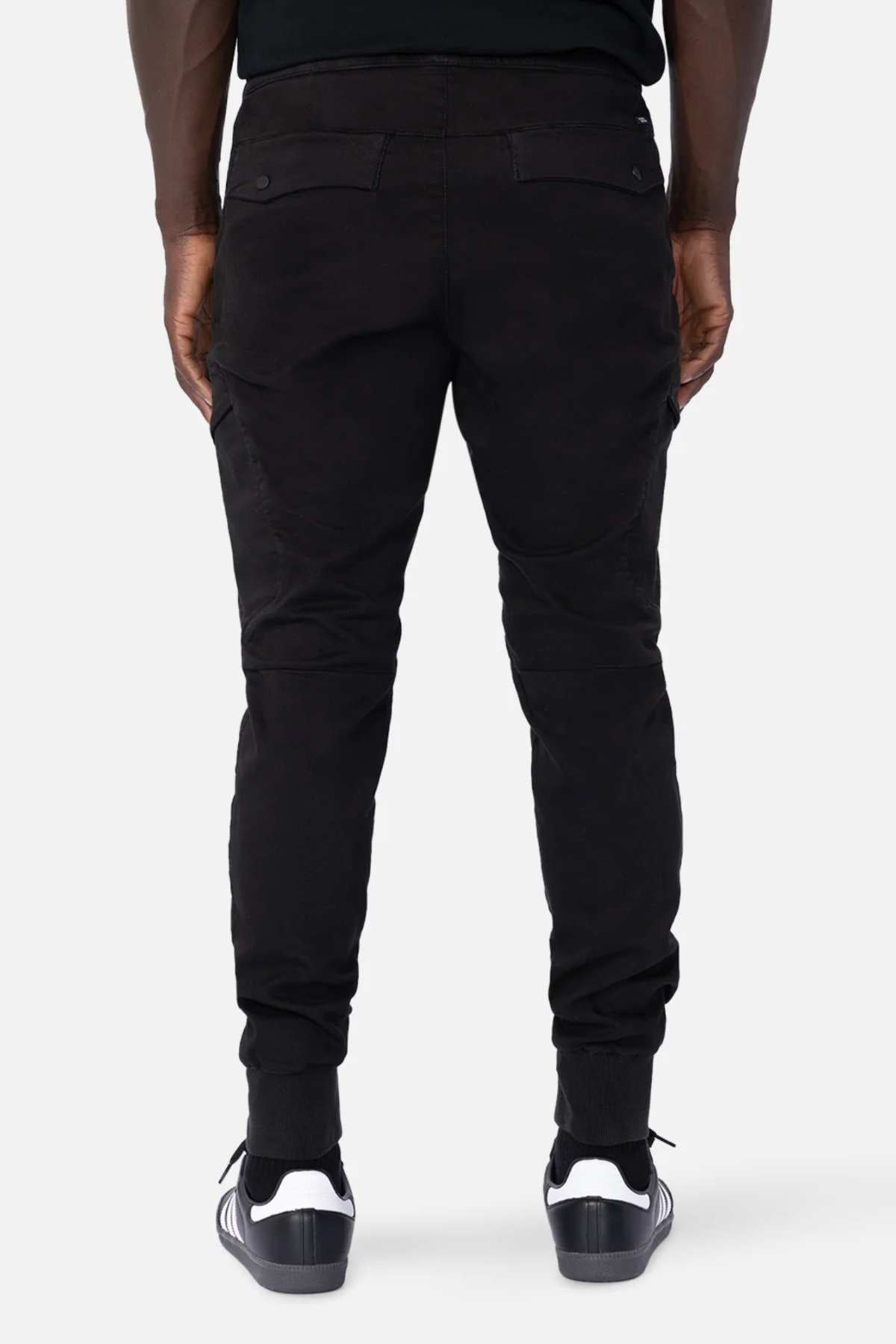 Rear view of a person immersed in their active lifestyle, wearing stylish black Industrie The Defender Combat Pants and sleek black sneakers with white soles, standing confidently against a neutral background.