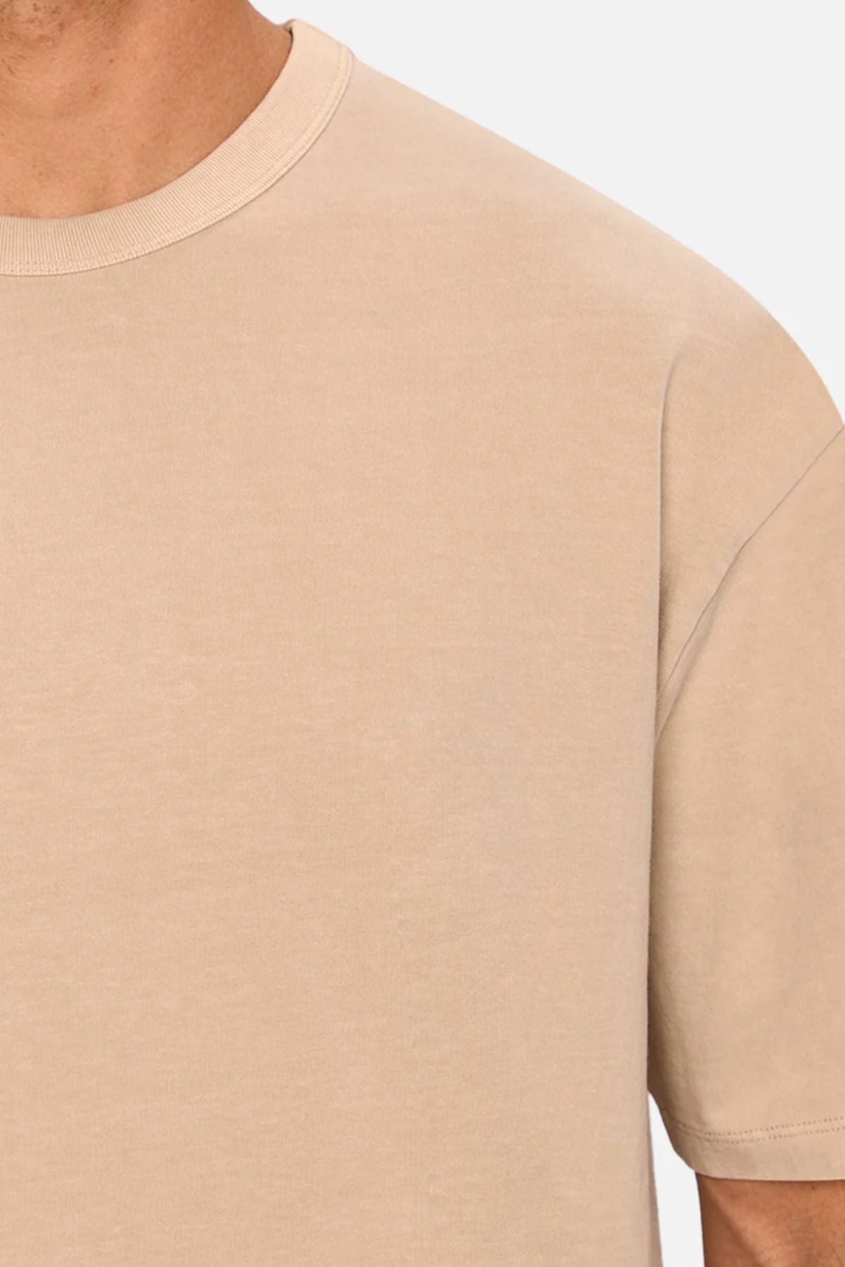 A close-up of someone wearing the Industrie The Del Sur Tee, an oversized beige shirt, highlighting the upper chest, shoulder, and neck.