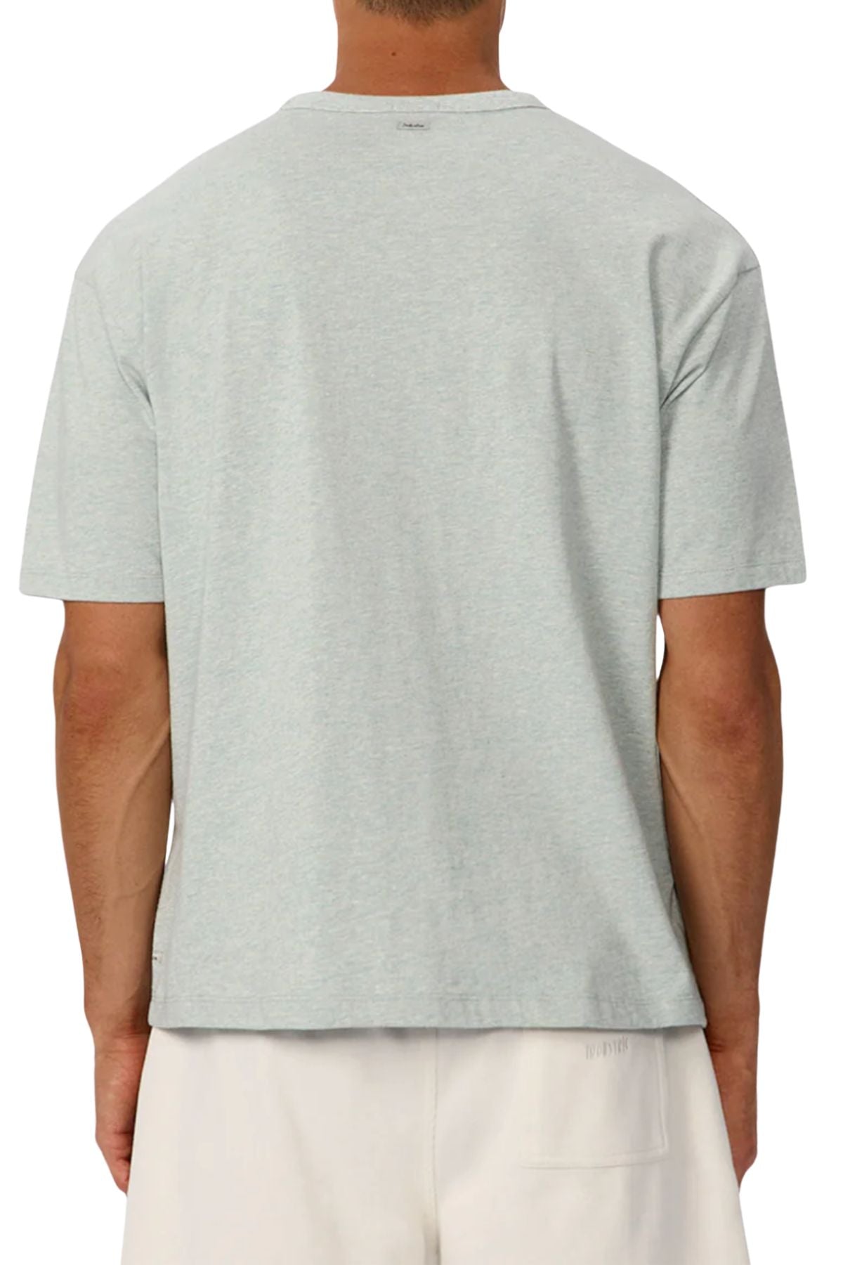 A person is shown from behind against a white background, wearing the Industrie The Del Sur Tee in light gray heavyweight fabric and off-white shorts.