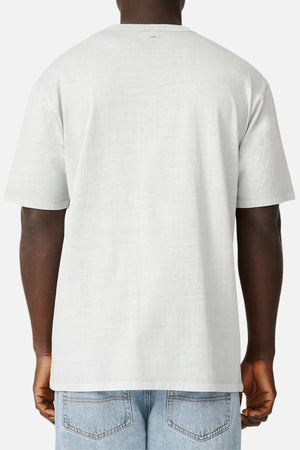 Rear view of a person wearing a light gray Industrie The Del Sur Tee in 100% cotton and blue jeans. The oversized fit adds comfort, and the tee features a small tag near the neckline. Their hands are relaxed by their sides against a plain white background.