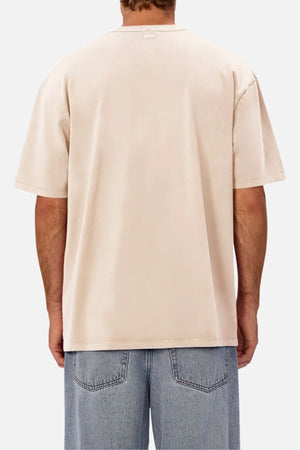 A person is seen from behind against a white background, wearing a loose, light beige Industrie The Del Sur Tee and blue jeans—the oversized t-shirt offers a relaxed and comfortable fit.