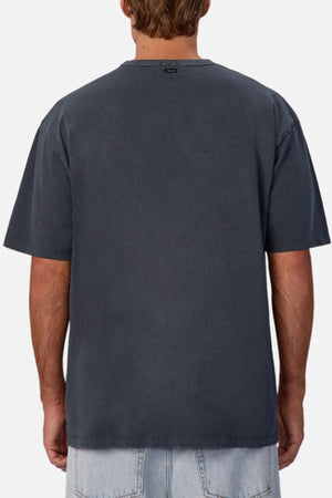A person is shown from the back wearing an oversized Industrie The Del Sur Tee in dark gray with light blue denim shorts against a plain background.