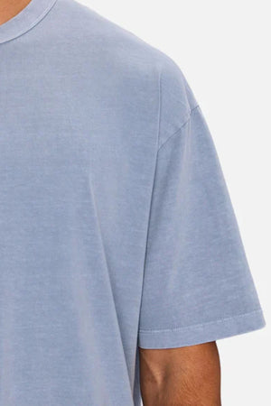 Cropped image of a person wearing the Industrie The Del Sur Tee in light blue. Only the left shoulder, sleeve, and part of the chest and arm are visible, showcasing the heavyweight fabric and oversized fit against a plain background.