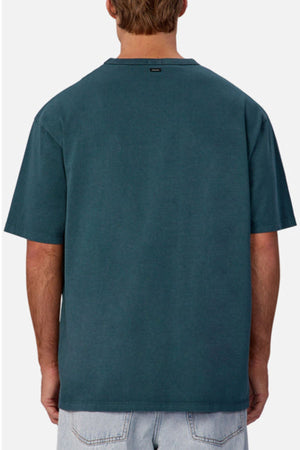 A person is shown from the back wearing an oversized Industrie The Del Sur Tee in plain teal with light blue denim shorts. The heavyweight cotton t-shirt stands out against the simple white background.