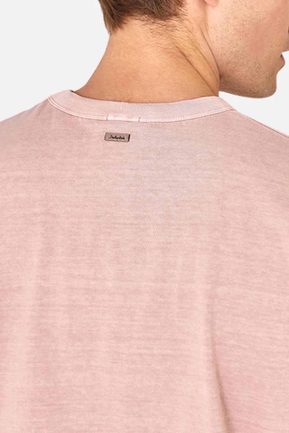 A rear view of someone wearing an Industrie The Del Sur Tee in light pink, displaying the upper back and neck with a small rectangular label below the neckline. The backdrop is plain and light gray.
