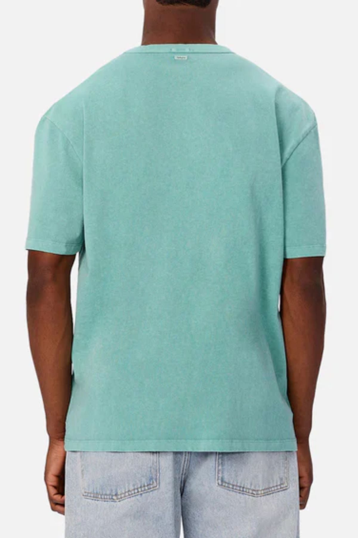A person is shown from behind wearing an Industrie The Del Sur Tee in plain teal and light blue jeans, standing against a light gray background.