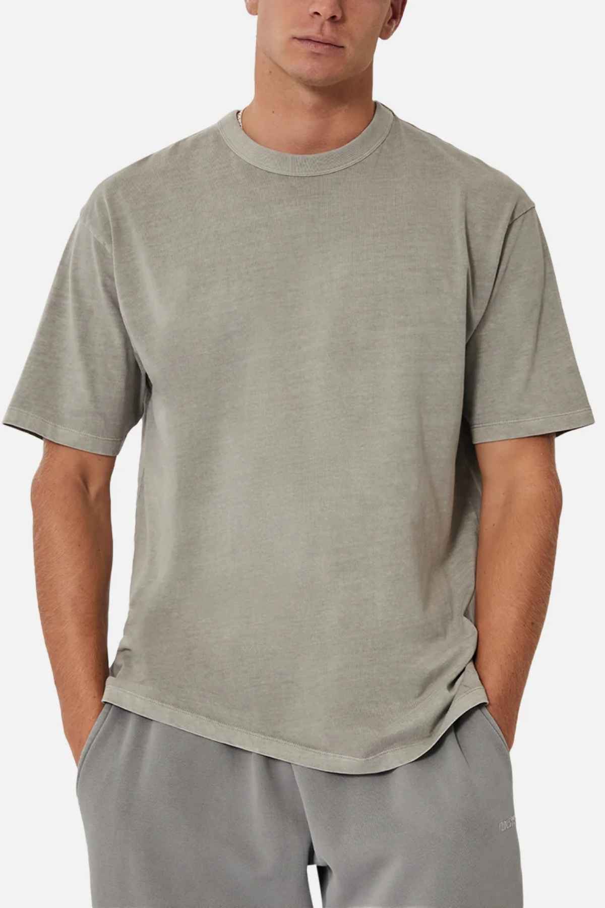 A person wearing an oversized, light gray Industrie The Del Sur Tee and matching acid wash pants stands with hands in pockets against a plain background.