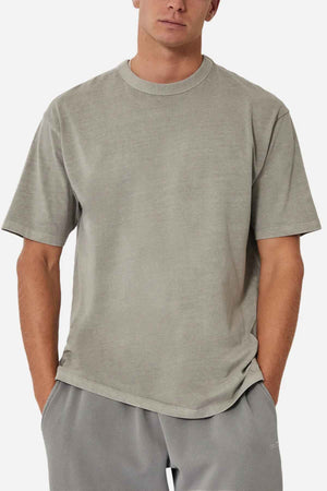 A person wearing an oversized, light gray Industrie The Del Sur Tee and matching acid wash pants stands with hands in pockets against a plain background.