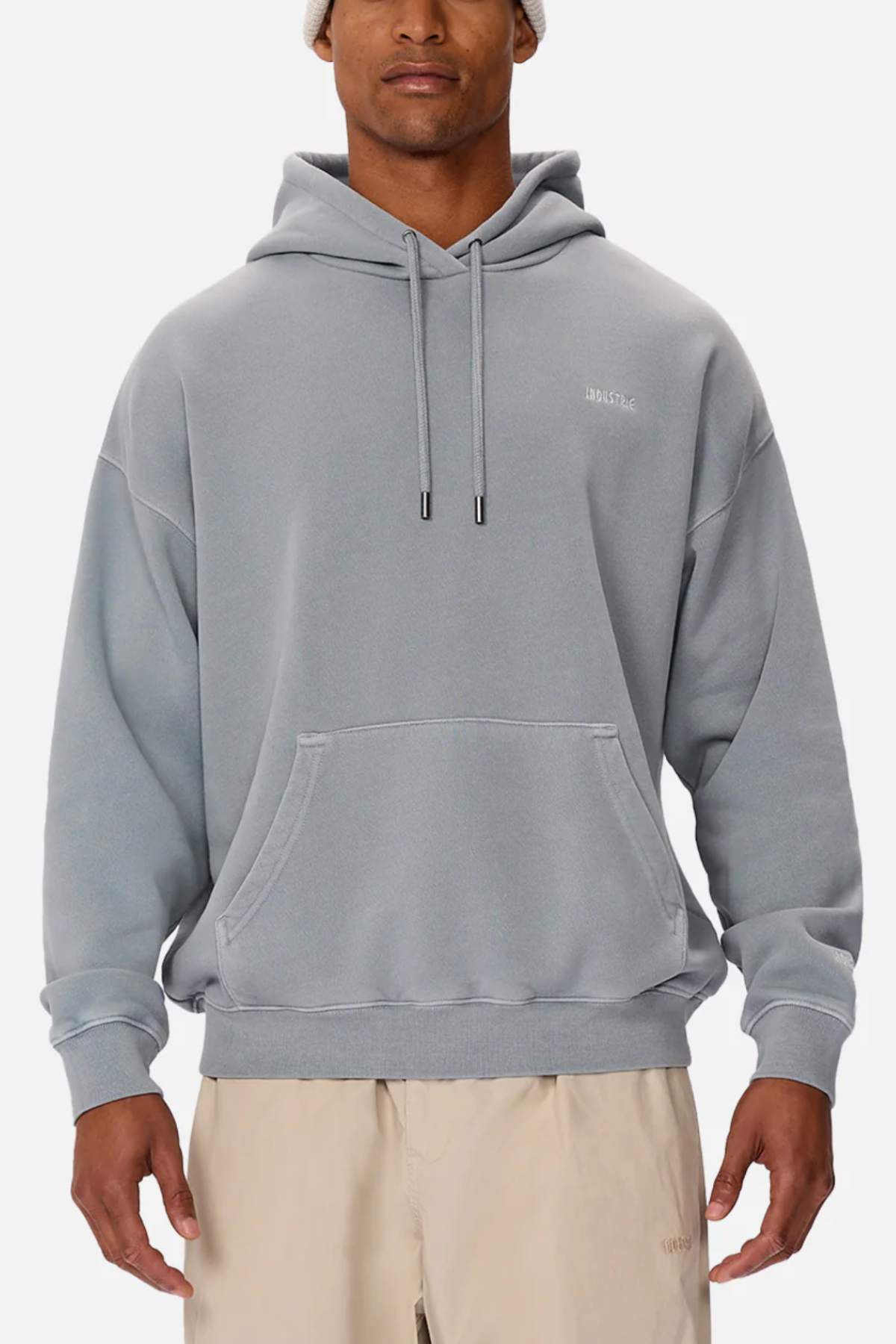 A person wearing the Industrie The Del Sur Washed Hoodie in light gray, styled oversized with a front pocket, and beige pants, stands against a plain white background.