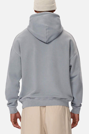 Someone wearing the Industrie The Del Sur Washed Hoodie in light gray with an oversized fit and beige pants, viewed from behind, standing against a plain white background.