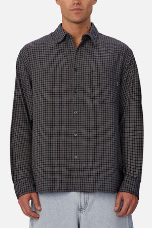 A person wears the Industrie The Diego Long Sleeve Shirt, a regular fit, long sleeve checked shirt in black and gray, paired with light blue jeans, standing against a plain white background.