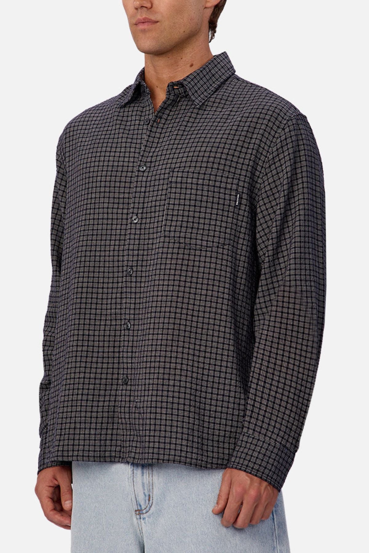 A person wearing the Industrie The Diego Long Sleeve Shirt in dark gray checks and light blue jeans stands against a plain white background, with their face partially out of frame.