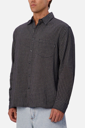A person wearing the Industrie The Diego Long Sleeve Shirt in dark gray checks and light blue jeans stands against a plain white background, with their face partially out of frame.