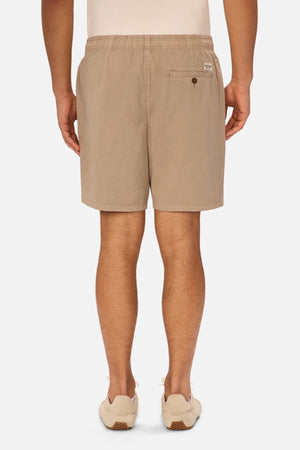 A person is standing facing away on a white background, wearing a white shirt, beige sneakers, and Industrie The Dublin Short—versatile summer shorts with an elastic waistband and back pocket.