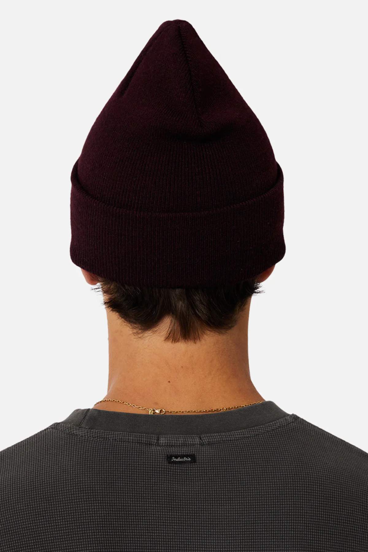 A person with short dark hair is seen from behind wearing a dark maroon beanie, the Industrie The Eastport Waffle Long Sleeve Tee in gray (made of 100% cotton), and a thin gold necklace. The background is plain white.