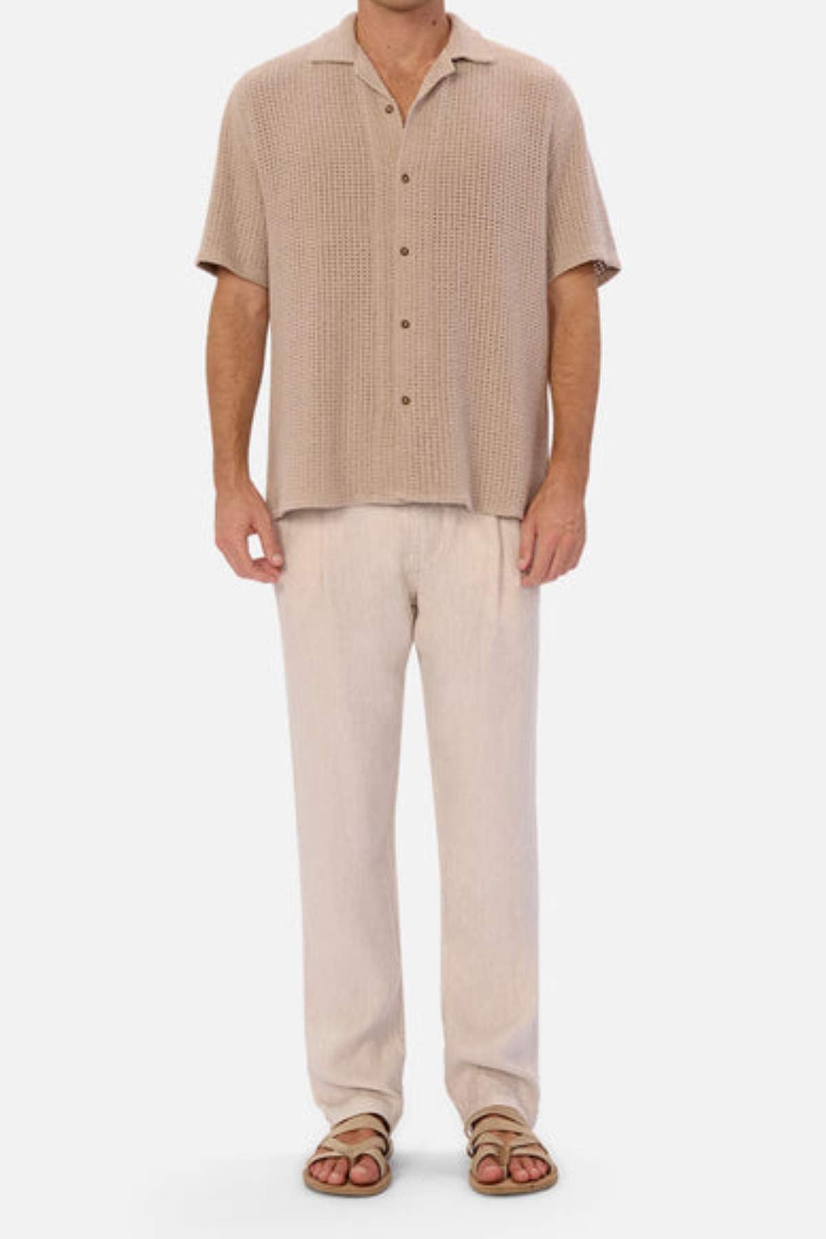 Wearing the Industrie The Egnazia Short Sleeve Shirt in beige, paired with light beige trousers and brown sandals, this ensemble crafted from a linen-cotton blend is ideal for a relaxed summer wardrobe against a plain white background.