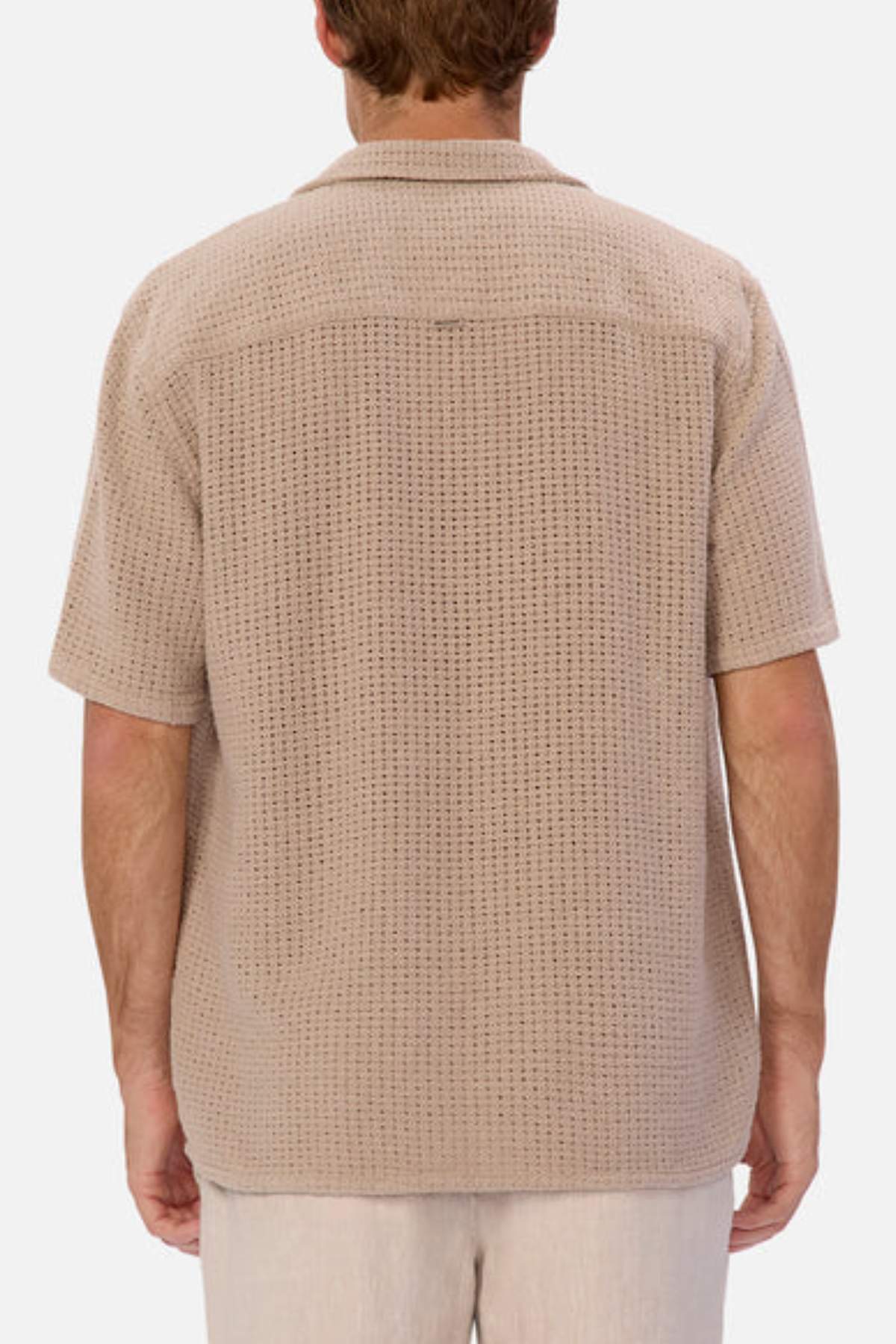 An individual with short brown hair wears the Industrie The Egnazia Short Sleeve Shirt, a beige, loose-fit shirt made from a linen-cotton blend, featuring a subtle textured pattern. They're viewed from the back against a plain white background. Perfect addition to any summer wardrobe.