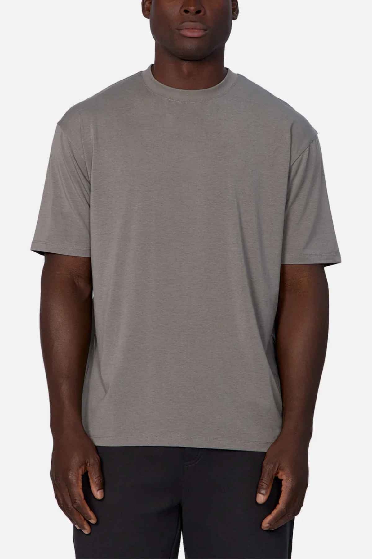 A person stands against a neutral background, dressed in dark pants and the Industrie The Freeman Athletic Tee. This T-shirt boasts a relaxed fit, short sleeves, and a crew neckline, highlighting the subtle branding of Industrie with its understated design.