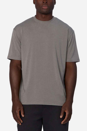 A person stands against a neutral background, dressed in dark pants and the Industrie The Freeman Athletic Tee. This T-shirt boasts a relaxed fit, short sleeves, and a crew neckline, highlighting the subtle branding of Industrie with its understated design.