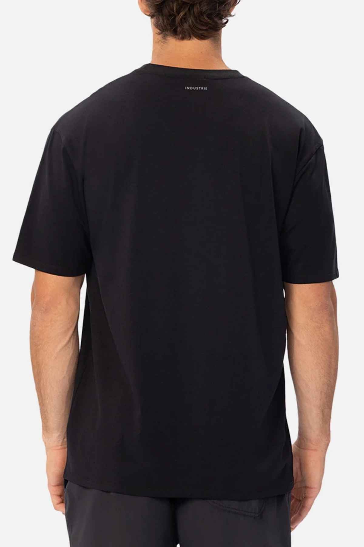 The image displays a person from behind wearing the Industrie The Freeman Athletic Tee, which is a relaxed-fit, plain black T-shirt paired with dark pants against a white background. This lightweight tee features a small logo located near the neckline at the top.