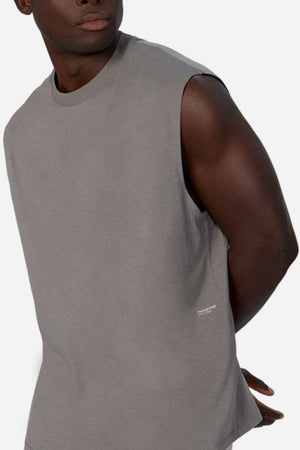 A man models the Industrie The Freeman Sleeveless Tee—featuring quick-dry technology—as he stands against a plain background, head turned to the side and arms positioned behind his back.