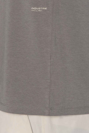 Close-up of the lower part of the Industrie The Freeman Sleeveless Tee in gray with "INDUSTRIE INCLINE" printed near the hem, paired with light-colored pants visible at the bottom.