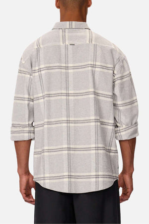 A person wearing the gray plaid Industrie The Gloucester Shirt, made from 100% cotton with a light gray and white checkered pattern, faces away. The sleeves are rolled up and paired with black pants against a plain white background.